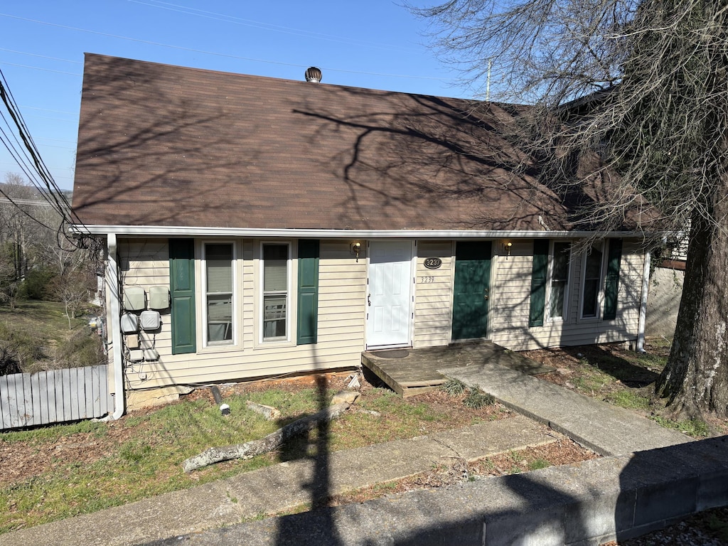 view of front of home with roof with shingles and fence