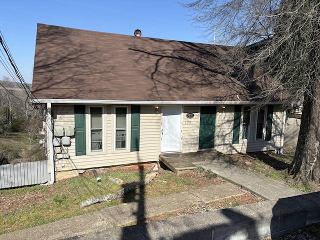 view of front of home with roof with shingles and fence