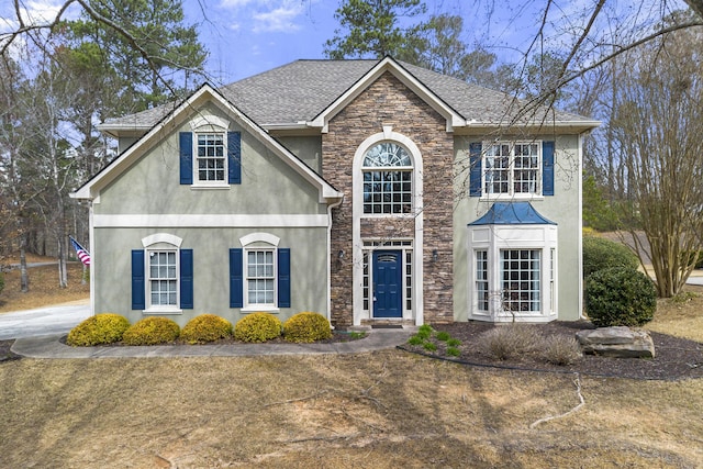 view of front of house with stucco siding, stone siding, and a shingled roof