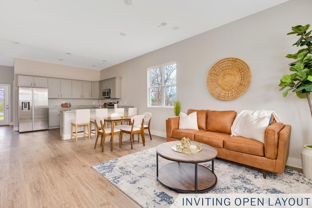 living area featuring light wood-style floors, visible vents, and baseboards