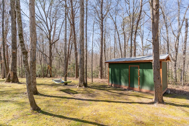 view of yard featuring an outbuilding, a storage unit, and a forest view