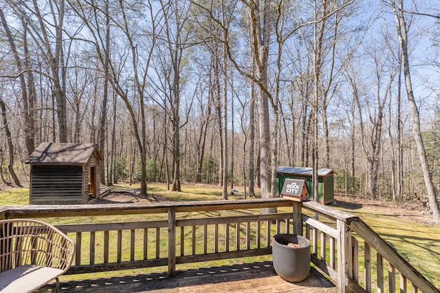 wooden deck with a storage shed, an outbuilding, and a forest view