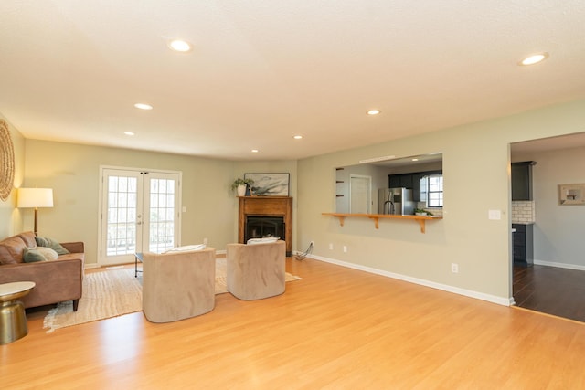 living room featuring wood finished floors, recessed lighting, french doors, a fireplace, and baseboards