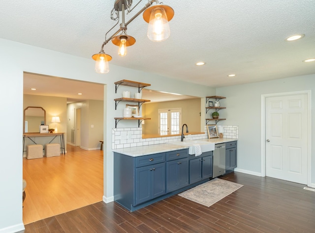 kitchen featuring open shelves, blue cabinets, dishwasher, and a sink