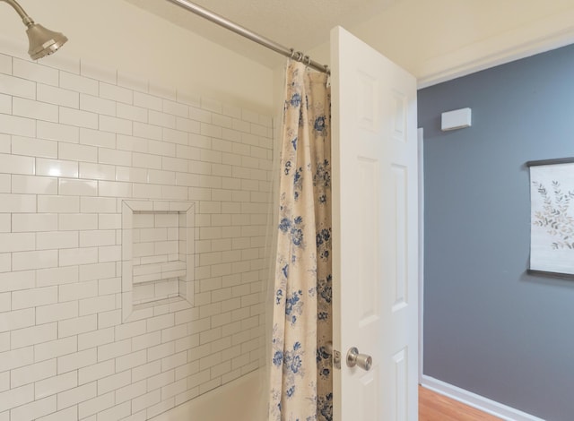 bathroom featuring baseboards and shower / bath combo with shower curtain