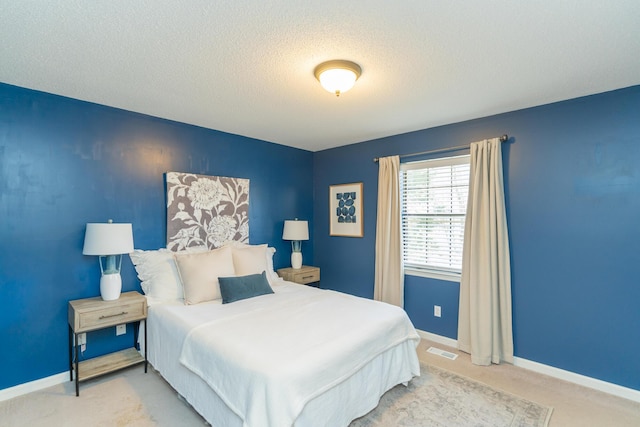 bedroom featuring baseboards, visible vents, carpet floors, and a textured ceiling