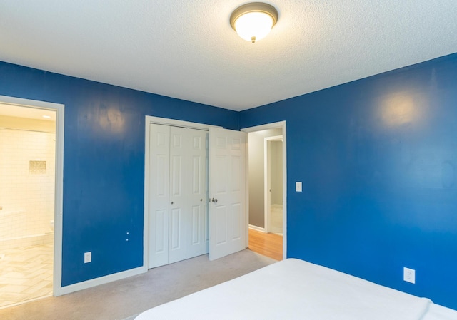 bedroom with connected bathroom, baseboards, a closet, and a textured ceiling