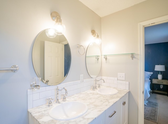 bathroom with a sink, connected bathroom, tasteful backsplash, and double vanity