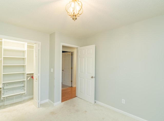 unfurnished bedroom with a closet, baseboards, light colored carpet, and a textured ceiling