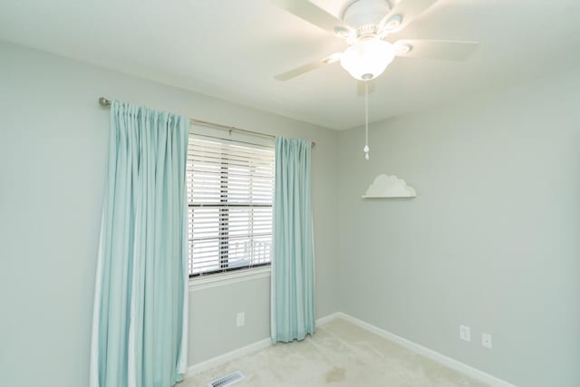 empty room featuring visible vents, light carpet, baseboards, and a ceiling fan