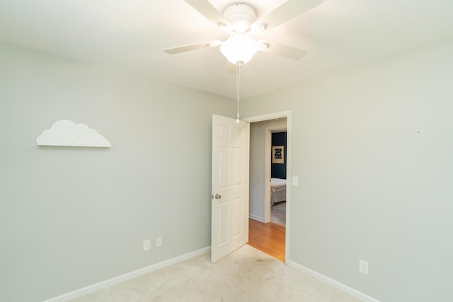 unfurnished room featuring a ceiling fan, light colored carpet, and baseboards