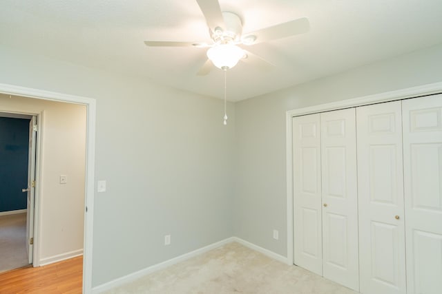 unfurnished bedroom with a closet, light colored carpet, a ceiling fan, and baseboards