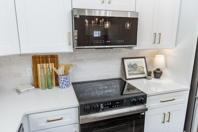 kitchen featuring decorative backsplash, stainless steel microwave, white cabinets, and range with electric cooktop