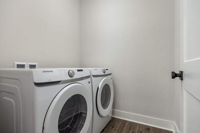 clothes washing area with dark wood finished floors, laundry area, baseboards, and washing machine and clothes dryer