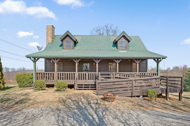 farmhouse with metal roof, a fire pit, a porch, and a chimney