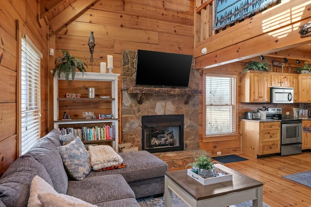 living room featuring light wood-type flooring, wooden walls, and a stone fireplace