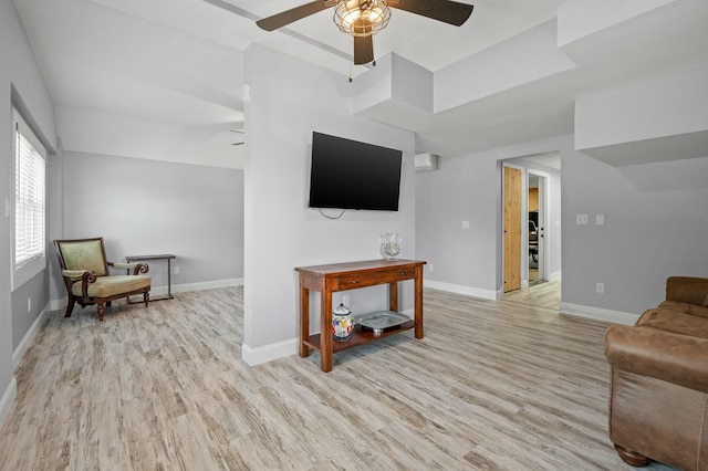 living area with baseboards, light wood-style flooring, and a ceiling fan