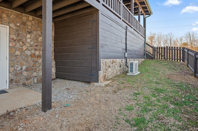 view of home's exterior featuring a fenced backyard, stone siding, and central AC