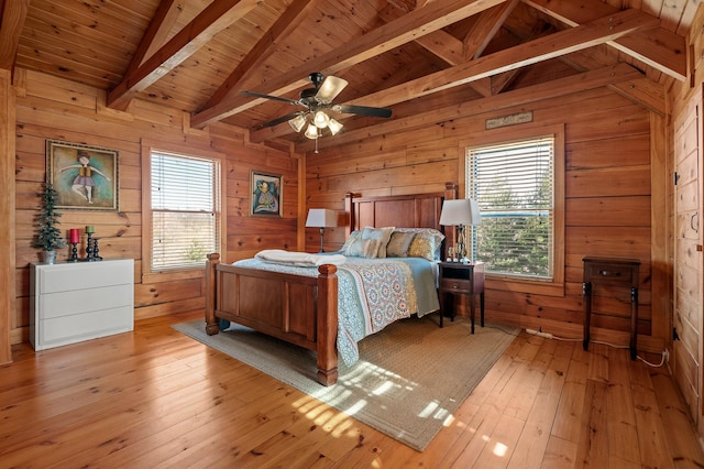 bedroom featuring lofted ceiling with beams, multiple windows, and wooden walls