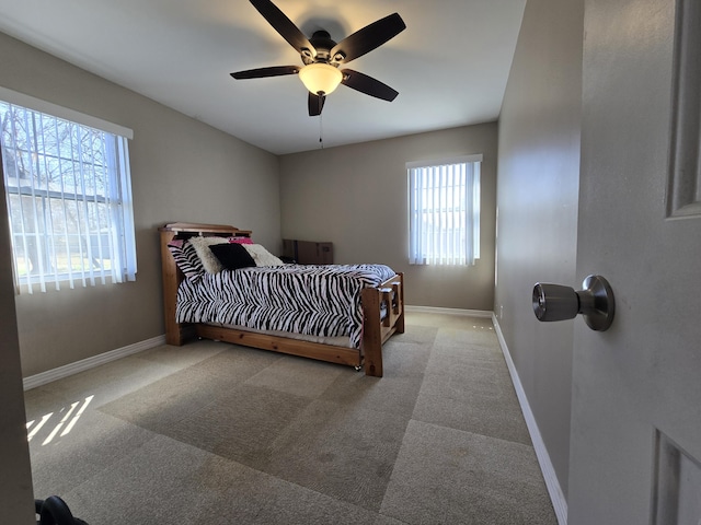 carpeted bedroom with multiple windows, a ceiling fan, and baseboards