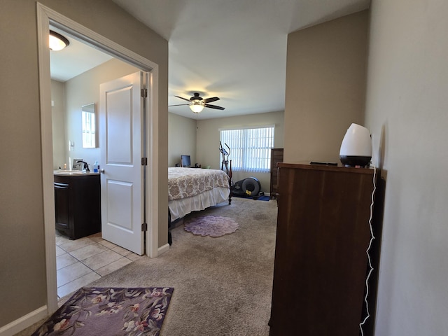 bedroom with a sink, light tile patterned floors, baseboards, light colored carpet, and ceiling fan