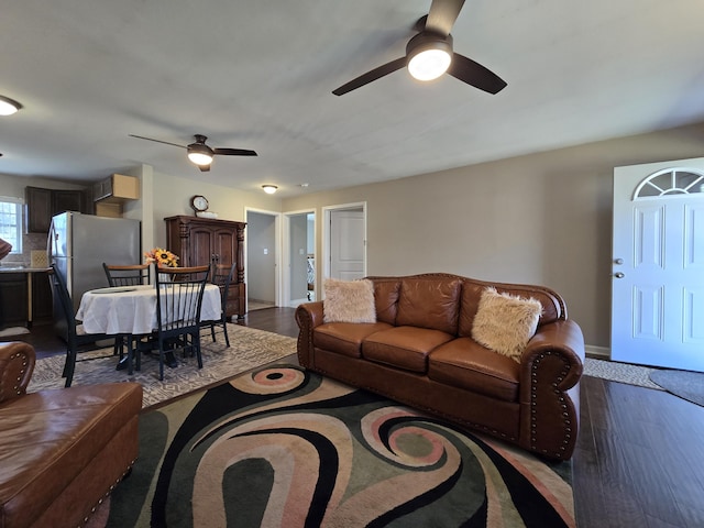 living room with baseboards, ceiling fan, and dark wood-style flooring