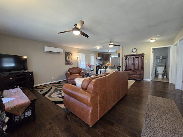 living area with dark wood finished floors, a ceiling fan, a wall mounted AC, and baseboards