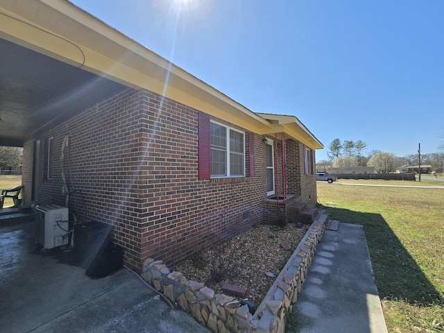 view of property exterior with brick siding, a lawn, and ac unit