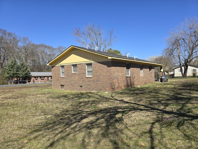 view of side of property with crawl space, brick siding, and a lawn