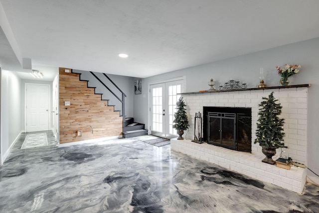 unfurnished living room with concrete floors, a brick fireplace, stairs, and french doors