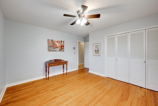 unfurnished bedroom featuring a closet, baseboards, light wood-style floors, and a ceiling fan