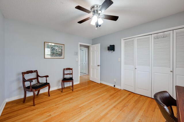 sitting room with ceiling fan, baseboards, a textured ceiling, and light wood-style flooring