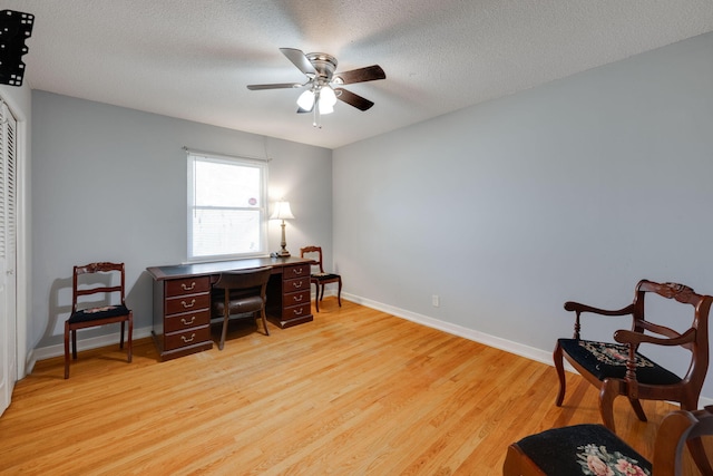 office with light wood finished floors, baseboards, a textured ceiling, and a ceiling fan