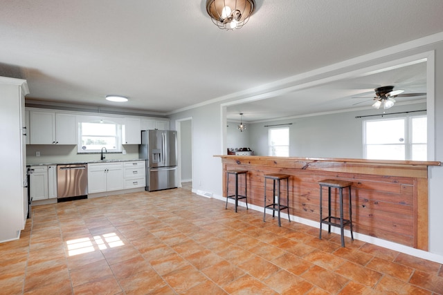 kitchen with visible vents, a ceiling fan, appliances with stainless steel finishes, white cabinets, and crown molding