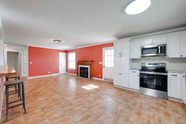 kitchen with a glass covered fireplace, light countertops, white cabinets, and appliances with stainless steel finishes