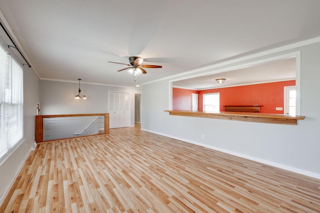 unfurnished living room featuring baseboards, wood finished floors, crown molding, and ceiling fan with notable chandelier