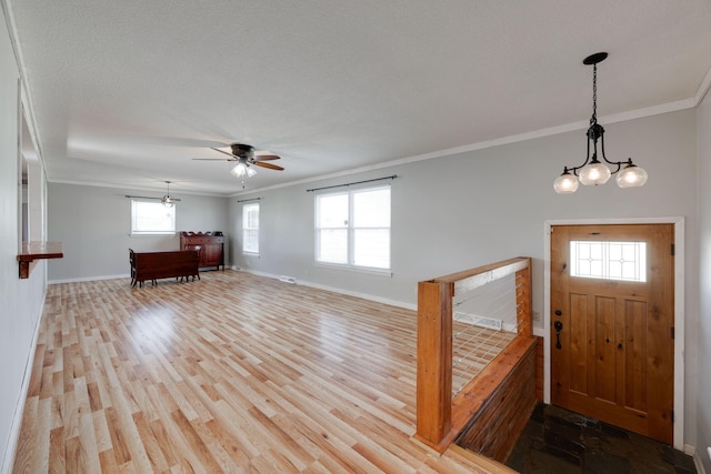 foyer entrance with ceiling fan with notable chandelier, crown molding, baseboards, and wood finished floors