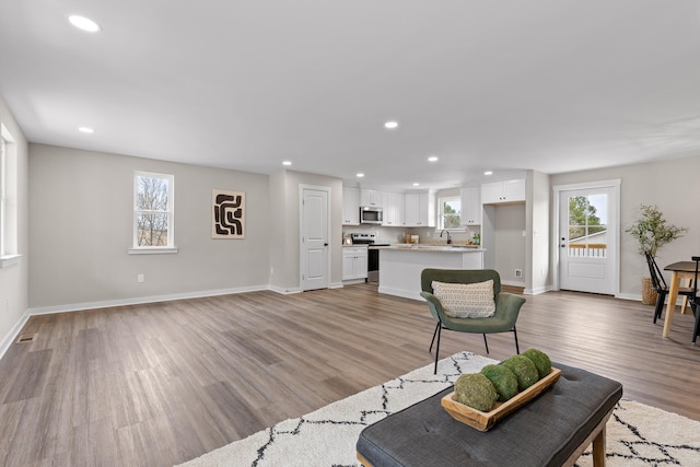 living area featuring visible vents, light wood-style flooring, recessed lighting, and baseboards