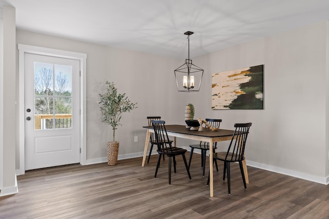 dining space with baseboards, an inviting chandelier, and wood finished floors