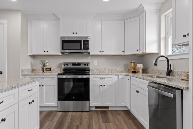 kitchen with a sink, appliances with stainless steel finishes, dark wood-style flooring, and white cabinetry