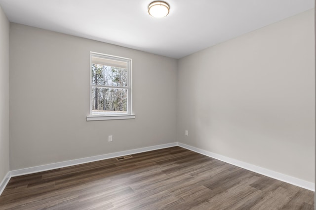 spare room with visible vents, dark wood-type flooring, and baseboards