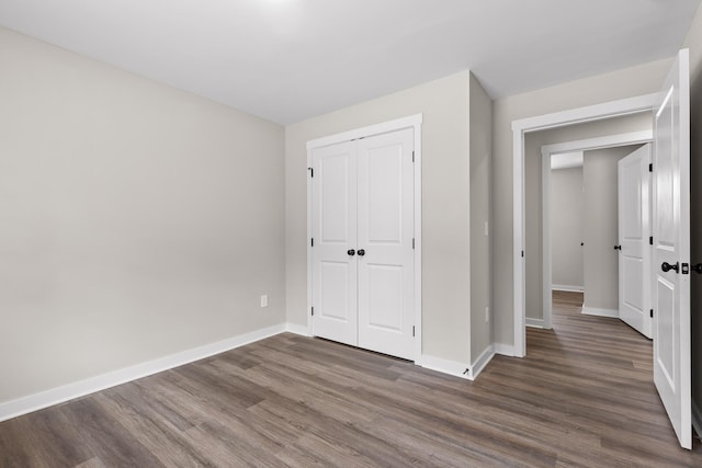 unfurnished bedroom with a closet, baseboards, and dark wood-style floors