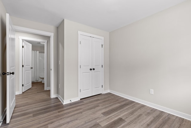 unfurnished bedroom with a closet, baseboards, and wood finished floors