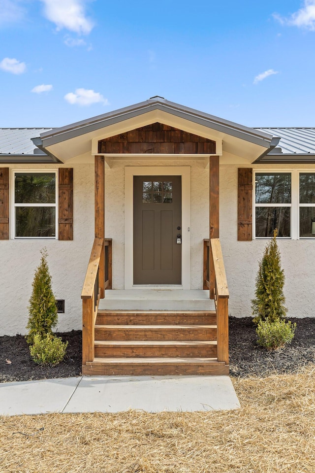 doorway to property featuring stucco siding, metal roof, and a standing seam roof