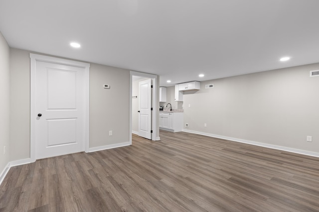 unfurnished living room with recessed lighting, wood finished floors, and baseboards