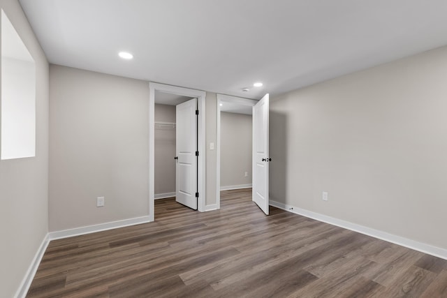 unfurnished bedroom with a spacious closet, recessed lighting, baseboards, and wood finished floors