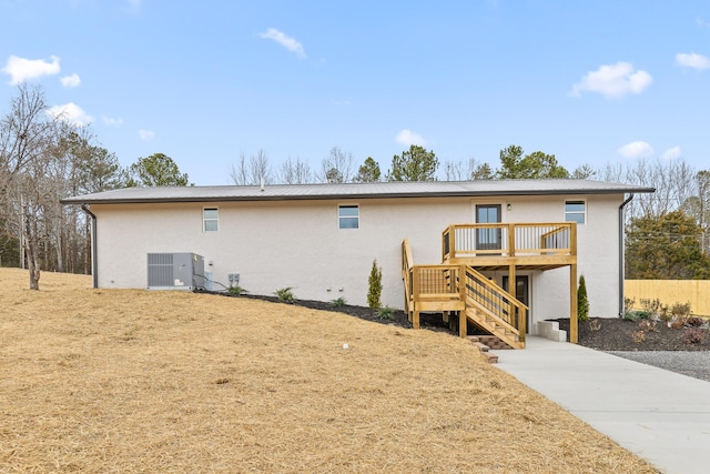 back of property with stairs, central AC, stucco siding, metal roof, and a deck