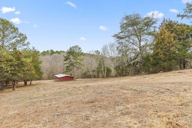 view of yard with a wooded view and an outdoor structure