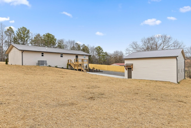 view of yard featuring cooling unit, an outbuilding, stairway, and fence