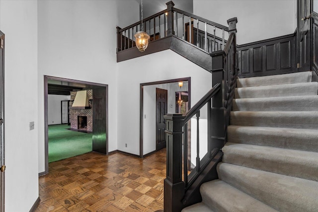 5803 Lake Resort Dr, Hixson, TN 37343 - staircase featuring a brick fireplace, baseboards, and a towering ceiling